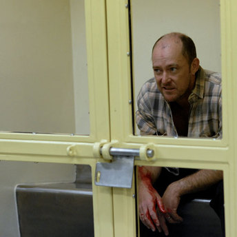 Bloodied man in a holding cell at the police station.